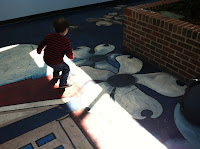 Toddler dancing around a floor mural