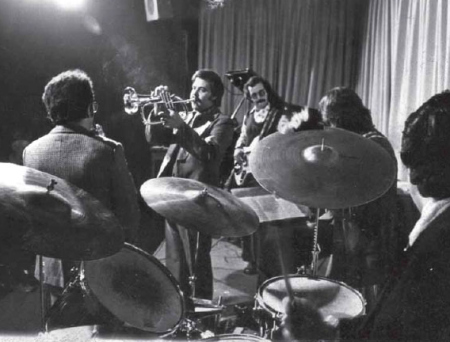 Aquila (Chile) "Aquila" (não confundir com a banda galesa de crossover prog com o mesmo nome) foi uma banda chilena de jazz rock fusion formada em 1973 pelo jovem compositor e vibrafonista "Guillermo Riffo", a banda ficou conhecida na história como o primeiro projeto substantivo no encontro do jazz com a música popular chilena. Como uma legítima banda híbrida, "Aquila" encontrou seu papel em uma variação de estilos no ponto de vista criativo, apesar da banda não sobreviver por muito tempo, essa fusão tornou-se um dos ramos mais fortes nos últimos 30 anos. Desde 1965, aos 19 anos, "Guillermo Riffo" já participava na seção de percussão da Orquestra Sinfônica do Chile. Em 1969 fundou o Grupo de Percussão da Universidade Católica e em 1971 ele já estava fazendo experimentações jazzísticas com o vibrafone (instrumento de percussão melódico), em conjunto com os irmãos "Roberto Lecaros" e "Mario Lecaros", seguindo a influência de seus clássicos ídolos como "Lionel Hampton", "Red Norvo" e "Milt Jackson". "Guillermo Riffo" em sua movimentação constante com a redescoberta da música popular, levou-o a encontrar-se com o baterista "Sergio Melli", que havia tocado até 1969 com os "Lecaros" no grupo "Village jazz group Trio". Como o epicentro de músicos que frequentavam a casa do pianista "Matias Pizarro" foi a fortaleza de "Riffo" e "Melli" para organizar e criar a "Aquila", desenvolvida no Rosso Nero Apumaque Shopping, que abriu espaços para o jazz às segundas-feiras e cujos proprietários foram "Melli" e o cantor pop "Paolo Salvatore". Em 1973, "Aquila" foi concluída como um quinteto e com uma diversidade de influências. Baseado no vibrafone de "Riffo", cuja influência foi na música clássica, e de fundo "Sergio Melli", baterista da geração do jazz moderno, e também teve a adição do saxofonista "Sandro Salvatti", pianista "Guillermo Olivares" (que até 1972 foi membro da banda de rock "Embrujo") e o baixista "Williams Miño" (com experiência em música popular). "Aquila" lançou seu único álbum auto-intitulado em 1974, através do selo "Alba", incorporando composições em sua maioria pertencentes ao "Riffo", bem como criações de outros membros do quinteto e peças do jazz moderno de "Pharoah Sanders" e "Herbie Hancock". A banda acabou rapidamente depois de algumas aparições contra o toque de recolher da cidade. Embora, como foi observado por "Alvaro Menanteau", musicólogo chileno, em seu livro "História do Jazz no Chile" de 2003, nesse curto espaço de tempo, a "Aquila" atingiu uma categoria fundamental na linha de misturas da música instrumental. Após a queda da cortina, "Guillermo Riffo" continuou a desenvolver a sua veia popular, musicalmente dirigiu o "Sexteto Hindetmith 76" (formado em 1973), mergulhou na raiz da música popular e em seguida foi para o grupo "Latinomúsicaviva" (formado em 1978), mais um dos projetos significativos do homem latino americano. Recomendo.