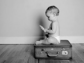 bebê sentado em cima de uma mala