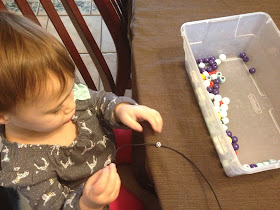 toddler playing with wooden beads