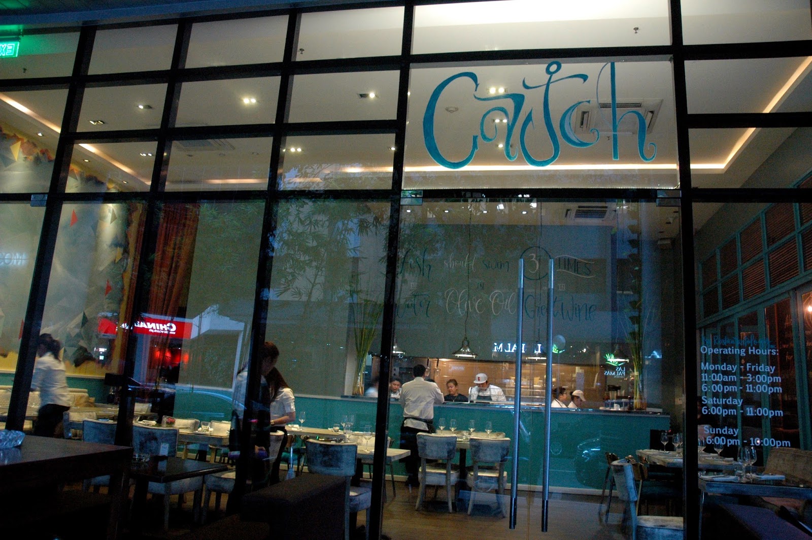 View in front of Catch Makati Gourmet Seafood Restaurant with people inside serving and eating