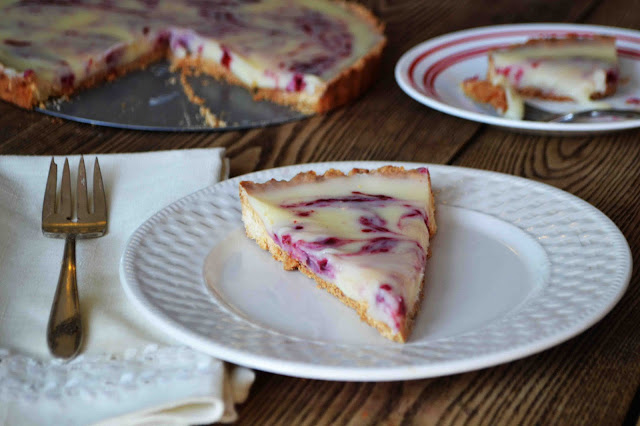 /></p> <p><br/> Ingredients:<br/> 1 1/4 cups flour<br/> 1/4 cup powdered sugar<br/> 1/2 tsp salt<br/> 1/2 tsp cinnamon<br/> 1/2 cup cold butter<br/> 1 egg yolk beaten<br/> (1-3 tsp's of milk if dough is too dry)<br/> <br/> FOR THE FILLING:<br/> 8 oz quality white chocolate (chopped<br/> 1 1/4 cups heavy cream<br/> 1/4 cup butter, room temperature<br/> 1/4 cup raspberry jam<br/> <br/> Directions:<br/> <br/> In a large mixing bowl combine the dry ingredients for your crust. Cut butter into to the mixture until it is shaggy and crumbly. Add in egg yolk. Work it into dough until you have the texture of oatmeal. If it is TOO dry add a bit of milk to bring it together more.<br/> <br/> Press dough into the bottom of a 9-10 inch tart pan with a removable bottom. Place in the freezer for 1 hour.<br/> <br/> Preheat oven to 350.<br/> <br/> Once the crust has set in the freezer for at least an hour, bake for 20 minutes or until golden brown.<br/> <br/> While the crust is baking start your filling. Heat cream to a very low simmer. In a separate pan add chocolate. Pour half of your heated cream over the chocolate whisking, while it starts melting slowly whisk in remaining cream. Once it is smooth and glossy whisk in the room temperature butter.<br/> <br/> Pour filling into your baked tart crust.<br/> <br/> Dollop small bits of jam all around your Tart. Drag a knife along the dollops to create a swirl look.<br/> <br/> Place tart in the refrigerator for at least 2 hours or until the chocolate has set.<br/> <br/> Serve cold. <br/> </p>