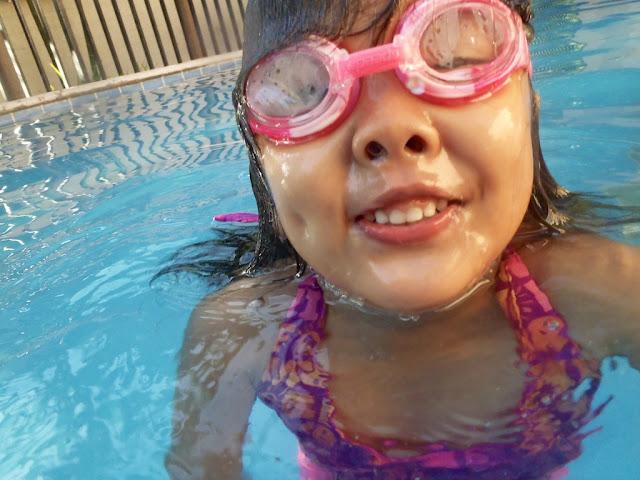Kecil with goggles smiling in the swimming pool