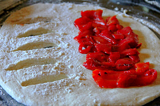 Fougasse bread dough rolled out with roasted red peppers on one half