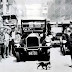 A traffic cop stops a busy street in New York City so a mother cat holding a kitten can cross safely, c.1925