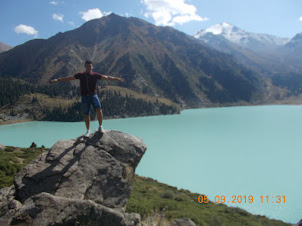Almaty Circus  Act :- Co Taxi traveller Mr Yeulan.Risbekov. posing on a rock with Big Almaty Lake .