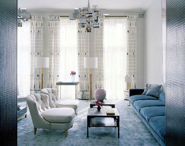 Patel living room in london with a blue velvet sofa, tufted lavender armchairs, blue carpet and a modern chandelier