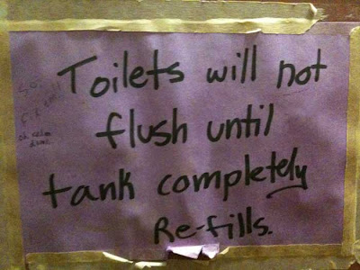 Purple construction paper sign with black marker lettering explaining that the toilet tank needs to refill before it can be flushed again