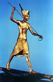 Gold figure of King Tutankhamun standing on a reed boat and spearing