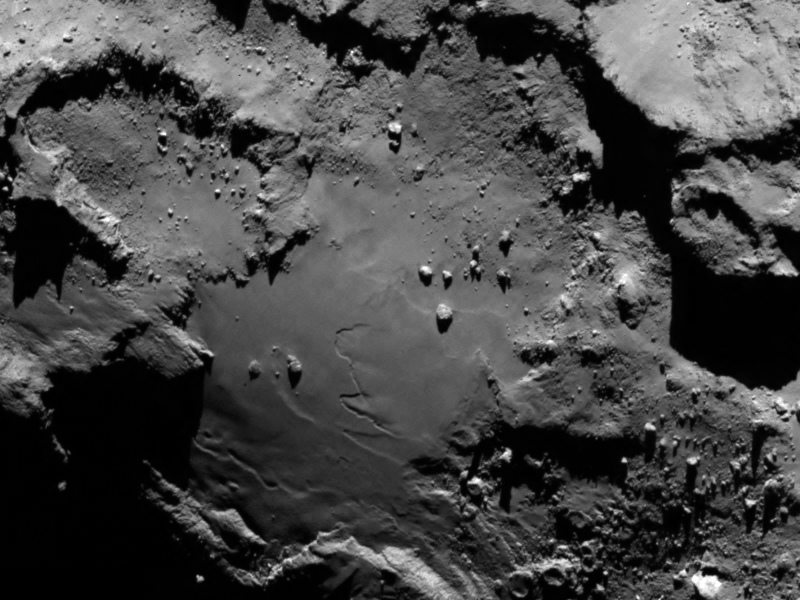Rosetta's Target Up Close Rosetta's Target Up Close  Close up detail focusing on a smooth region on the ‘base’ of the ‘body’ section of comet 67P/Churyumov-Gerasimenko. The image was taken by Rosetta’s Onboard Scientific Imaging System (OSIRIS) on August 6, 2014. The image clearly shows a range of features, including boulders, craters and steep cliffs. The image was taken from a distance of 80 miles (130 kilometers) and the image resolution is 8 feet (2.4 meters) per pixel.  The three U.S. instruments aboard the spacecraft are the Microwave Instrument for Rosetta Orbiter (MIRO), an ultraviolet spectrometer called Alice, and the Ion and Electron Sensor (IES). They are part of a suite of 11 science instruments aboard the Rosetta orbiter.  MIRO is designed to provide data on how gas and dust leave the surface of the nucleus to form the coma and tail that gives comets their intrinsic beauty. Studying the surface temperature and evolution of the coma and tail provides information on how the comet evolves as it approaches and leaves the vicinity of the sun.  Alice will analyze gases in the comet's coma, which is the bright envelope of gas around the nucleus of the comet developed as a comet approaches the sun. Alice also will measure the rate at which the comet produces water, carbon monoxide and carbon dioxide. These measurements will provide valuable information about the surface composition of the nucleus.  NASA also provided part of the electronics package for the Double Focusing Mass Spectrometer, which is part of the Swiss-built Rosetta Orbiter Spectrometer for Ion and Neutral Analysis (ROSINA) instrument. ROSINA will be the first instrument in space with sufficient resolution to be able to distinguish between molecular nitrogen and carbon monoxide, two molecules with approximately the same mass. Clear identification of nitrogen will help scientists understand conditions at the time the solar system was formed.  U.S. scientists are partnering on several non-U.S. instruments and are involved in seven of the mission's 21 instrument collaborations. NASA's Deep Space Network is supporting ESA's Ground Station Network for spacecraft tracking and navigation.  Launched in March 2004, Rosetta was reactivated in January 2014 after a record 957 days in hibernation. Composed of an orbiter and lander, Rosetta's objectives upon arrival at comet 67P/Churyumov-Gerasimenko in August are to study the celestial object up close in unprecedented detail, prepare for landing a probe on the comet's nucleus in November, and track its changes as it sweeps past the sun.  Comets are time capsules containing primitive material left over from the epoch when the sun and its planets formed. Rosetta's lander will obtain the first images taken from a comet's surface and will provide the first analysis of a comet's composition by drilling into the surface. Rosetta also will be the first spacecraft to witness at close proximity how a comet changes as it is subjected to the increasing intensity of the sun's radiation. Observations will help scientists learn more about the origin and evolution of our solar system and the role comets may have played in seeding Earth with water, and perhaps even life.  Image Credit: ESA/Rosetta/MPS for OSIRIS Team Explanation from: http://www.nasa.gov/content/rosettas-target-up-close/