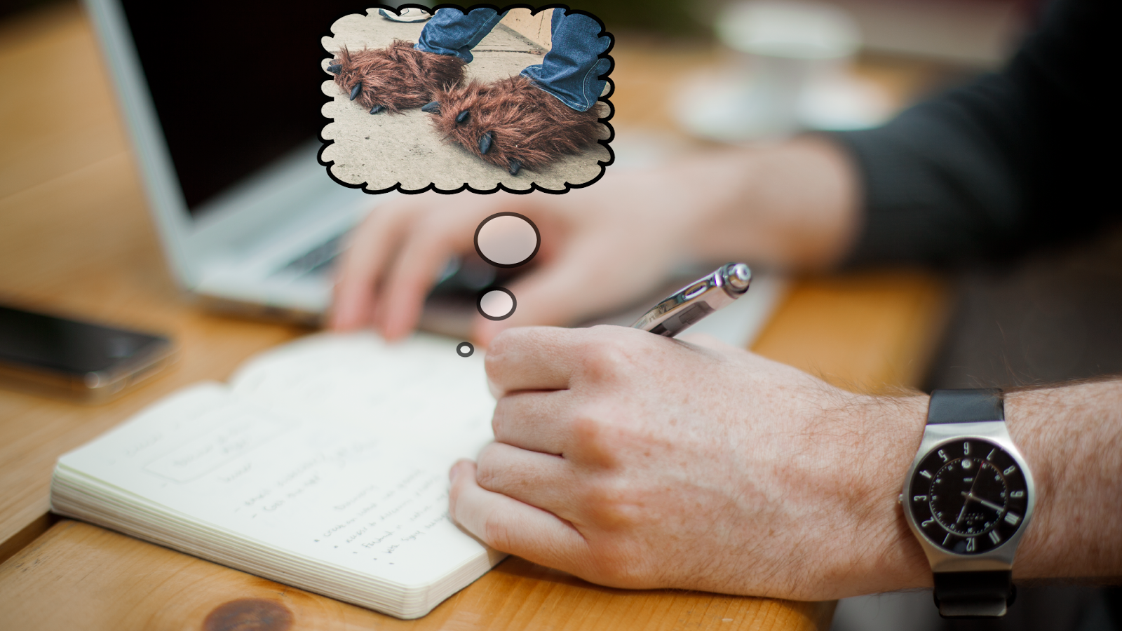 Man sitting at desk writing in a journal, only his arms, desk, notebook, pen and a computer in the background are visible.  A thought bubble rising up from the notebook depicts "bear feet": a picture of someone wearing bluejeans and brown fuzzy clawed monster slippers.