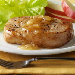 Picture of Pork Chops with Cider Sauce and Parsley with lettuce and apples on a white plate and a fork