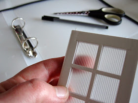 Modern dolls house miniature French door with frost insert. In the background is a opaque plastic ring binder, a pen and a pair of scissors.
