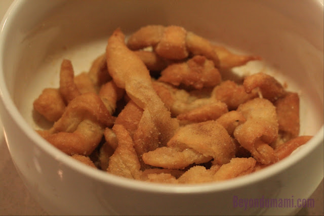 Bowl of left-over puff pastry scraps deep-fried and sprinkled with sugar.