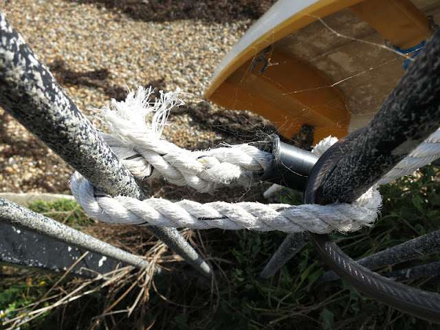 White rope tied to railings in front of rowing boat on sandy beach