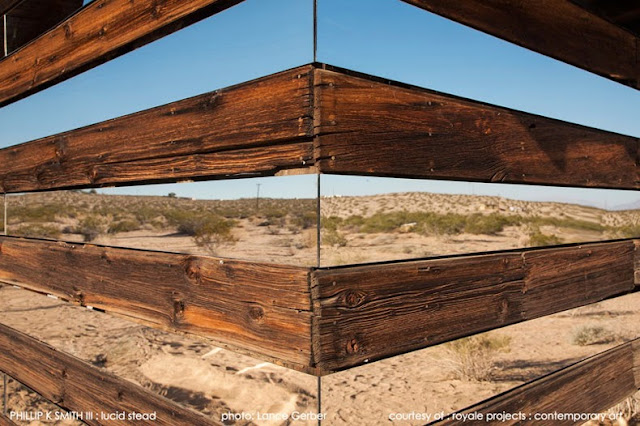 Cabaña transparente de madera y espejos en un paisaje desértico