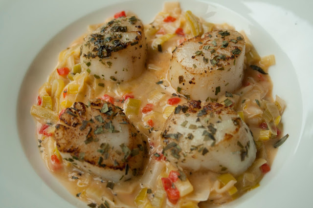 Sint-jakobsnootjes met verse kruiden op een preibedje