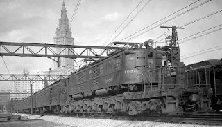 From about 1950, a diesel locomotive railroad train with Terminal Tower in far background