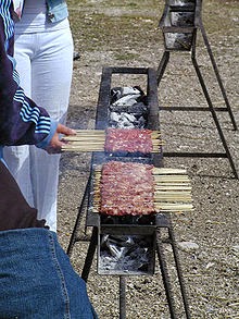 Grilling marinated shashlik preparing on a barbecue grill over charcoal.  Shashlik is a form of Shish kebab popular in Eastern Europe. Shashlyk (meaning  skewered meat) was originally made of lamb. Stock Photo