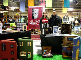 The Suitcase Dollhouse stall at the Old Bus Depot Markets at Kingston, with owners Marisa and David next to their banner.