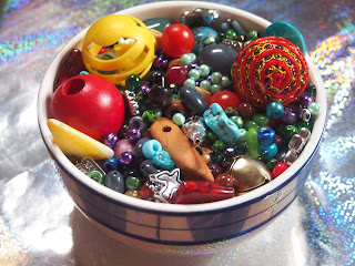 a bowl filled with beads of all sizes, shapes, colors, randomly