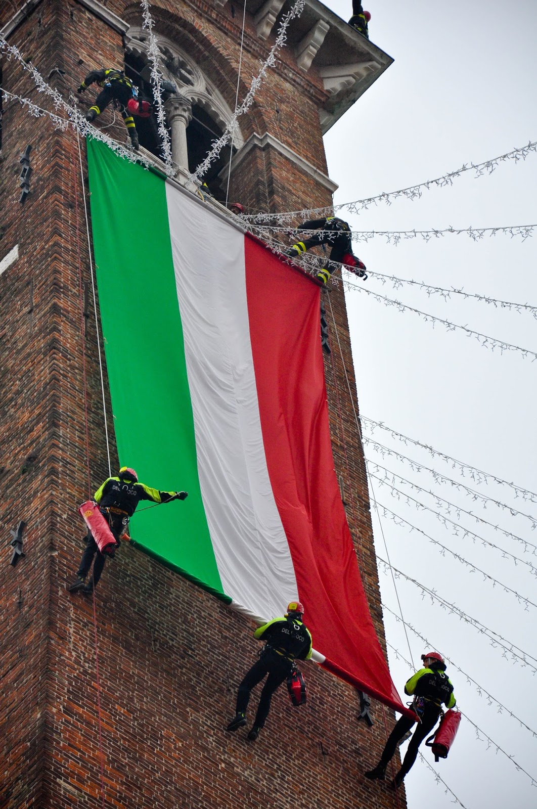 Firefighters unfurling the Italian flag down the clock tower of Palladio's Basilica, Saint Barbara celebration, Vicenza, Veneto, Italy