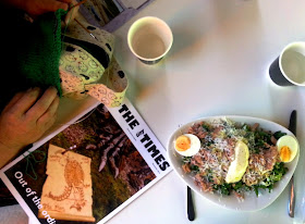 Some knitting, a copy of The tiny Tomes and a tuna nicoise salad on a cafe table.