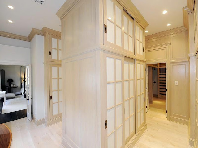Enormous walk in closet in the master bedroom with light wood storage cabinets and wardrobes