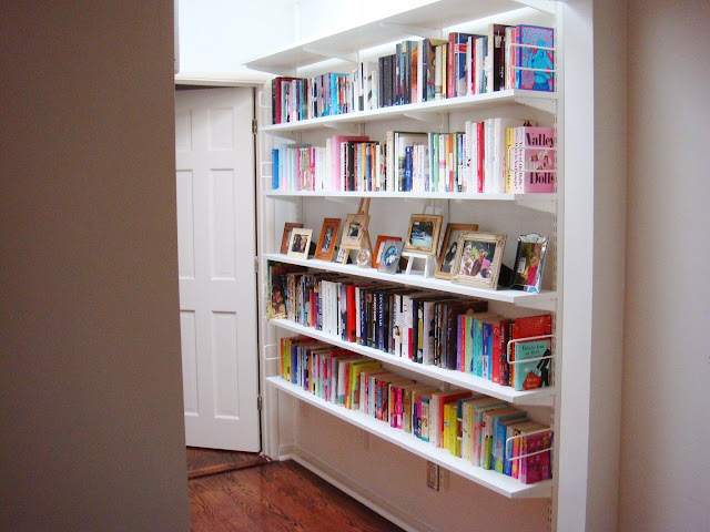 sleek, light, bright and white hallway library full of colorful books and framed photos