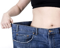 Woman holding out extra large waistband on jeans indicating weight loss