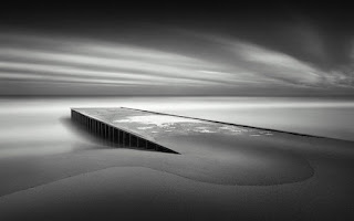 [spiaggia di sabbia con un ponte dove si vede il cielo]