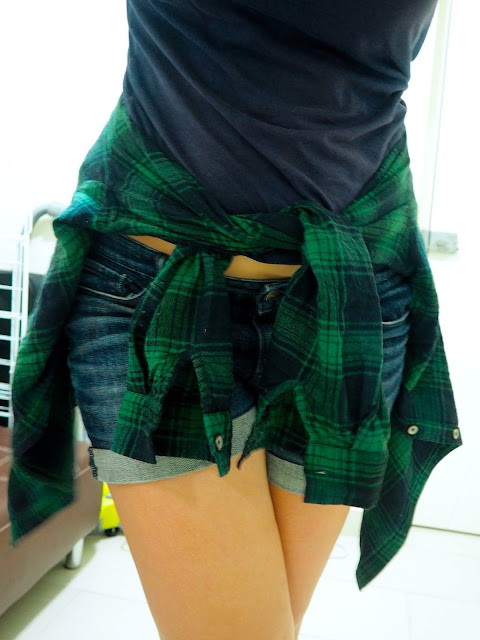 Tartan Takeover | outfit close up details of green checked / plaid / tartan shirt tied around the waist, with denim shorts