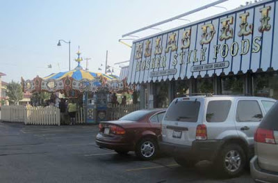 Ella's Deli exterior, circus-like lettering, with a carousel in the background