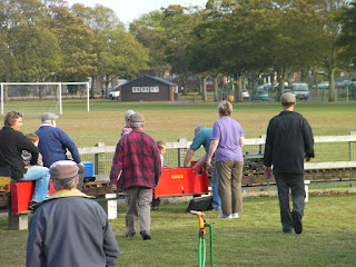 green miniature steam train broken down with engineers