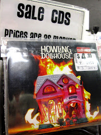 CD by the band Howling Dollhouse with a picture of a burning Fisher Price dollhouse on the front cover, in the sale bin.