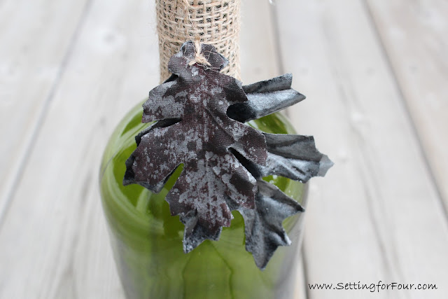 DIY Wine Bottle Candle Holder with painted leaf garland.
