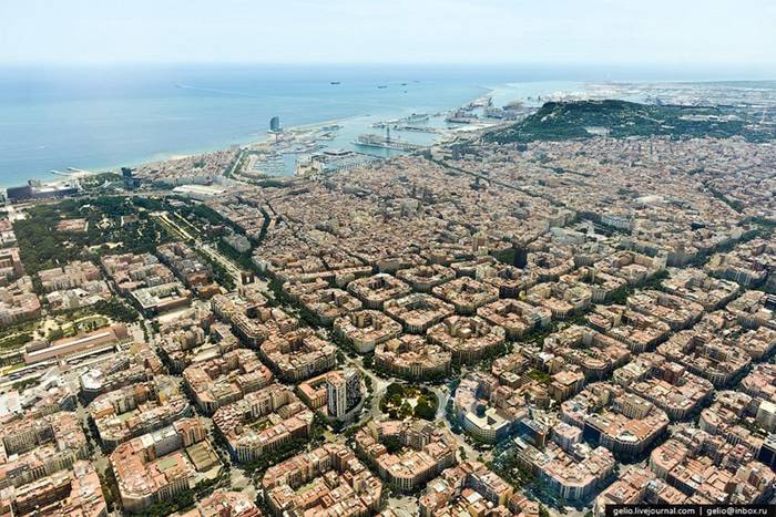 Aerial View of City Eixample — Barcelona Eixample is a district of the Spanish city of Barcelona, that lies between the old city and the surrounding small towns. The district was built as an extension (hence the name “Eixample”) when Barcelona started to grow during the middle of the 19th century. The 7.5 square km district is characterized by long straight streets, a strict grid pattern crossed by wide avenues, and octagonal city blocks - rectangular blocks with the corners cut off, which are distinctive for Barcelona. This was the visionary, pioneering design by Spanish urban planner Ildefons Cerdà, who considered traffic and transport along with sunlight and ventilation in coming up with his characteristic octagonal blocks.