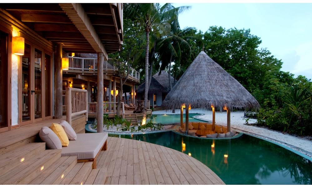 Photo of the beach and swimming pool as seen from the wooden porch of one of the resort residences