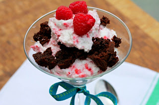 rasbperry fool in a martini glass with chunks of brownie and fresh raspberries on top