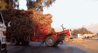 east european or russian overloaded tractor funny trailer overloaded with hay straw makes tractor do a wheelie