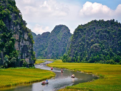 Tam Coc - Bich Dong The Tam Coc (“three caves”) portion is a three-hour excursion by small boat along the Ngô Đồng river, beginning at the village of Van Lam and proceeding through a scenic landscape dominated by rice fields and karst towers. The route includes floating through three natural caves (Hang Ca, Hang Hai, and Hang Ba), the largest of which is 125m long with its ceiling about 2m high above the water. The boats are typically rowed by one or two local women who also sell embroidered goods.