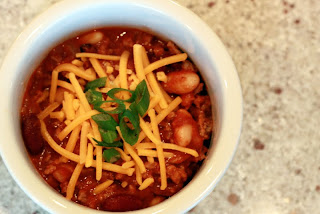 bowl of chili with cheese and green onions