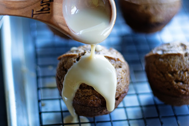 A pumpkin muffin with the latte glaze being spooned over the top of it.  