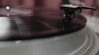 Close up of the needle of a record player with a spinning vinyl underneath