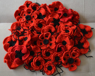 A pile of crocheted poppies of different designs.  