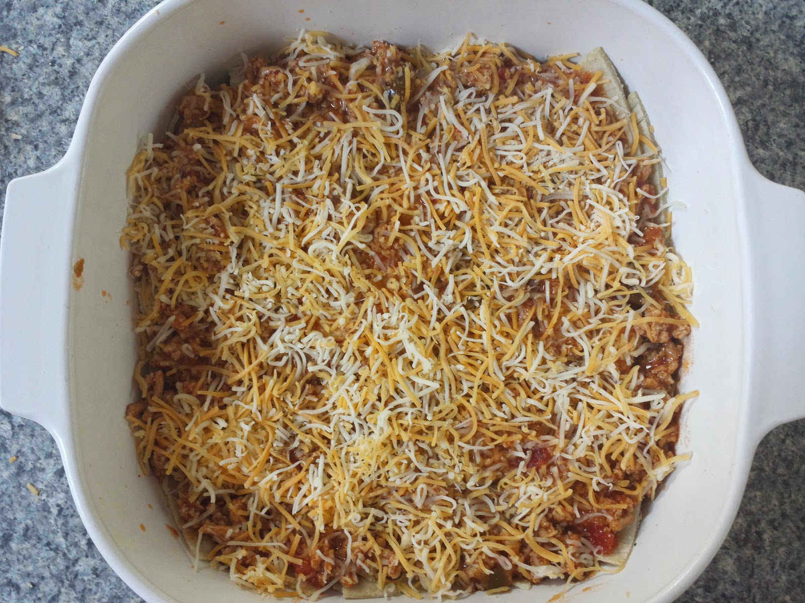 adding cheese to the enchilada bake
