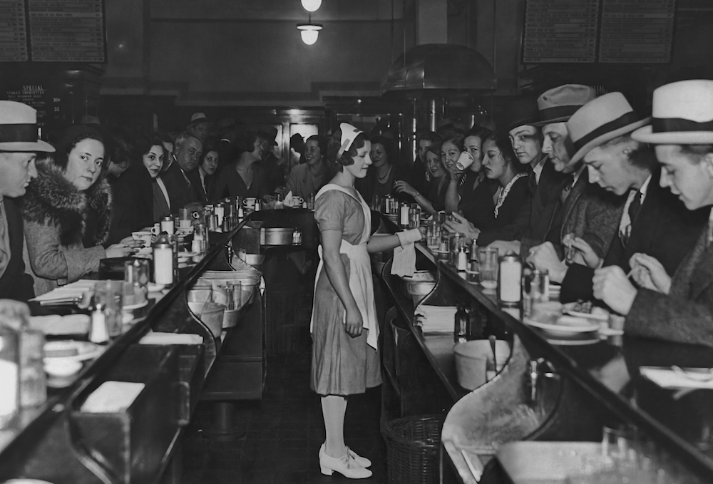 A waitress stands in the middle of the counters during lunch time at