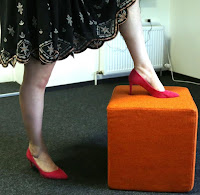 Girl Pumps auf orangenen Hocker Gril Pumps in rot auf einem Hocker