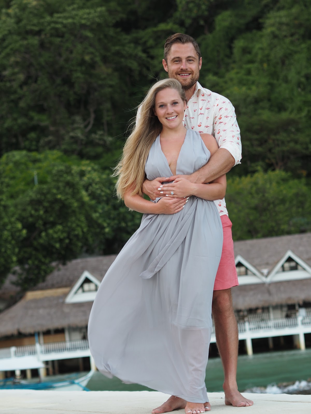 Engaged Couple in lovely outfits on a pier with the sea behind