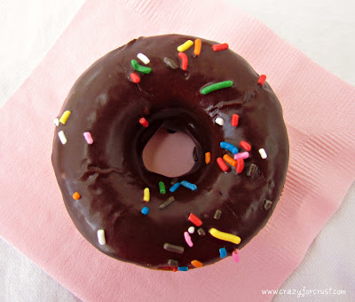 funfetti donuts with chocolate glaze and sprinkles on pink napkin